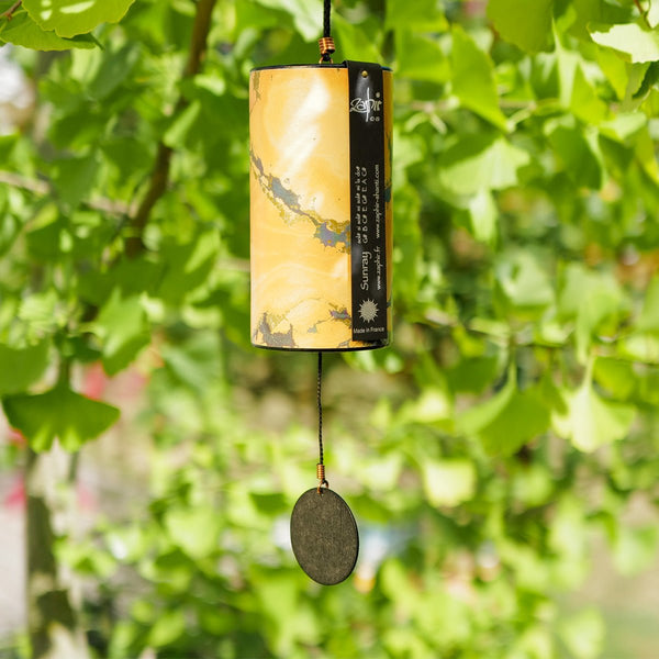 Zaphir Sunray wind chime in yellow, handcrafted cellulose resonance tube with eight silver-welded metal cords, Summer season, made in France, Ginkgo Tree in the Background
